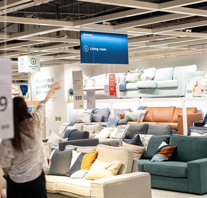a woman holding a sign in a furniture store